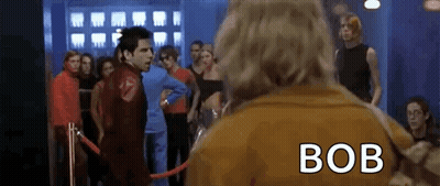 Man In Brown Jacket With Bob On Back In Crowd GIF