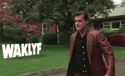 Man In Brown Leather Jacket Standing In Front Of House With Waklyf On Sidewalk GIF