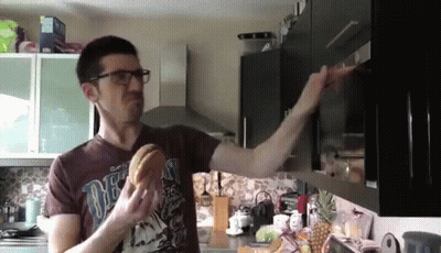 Man In Brown Shirt Saying One Eating Hamburger In Kitchen GIF