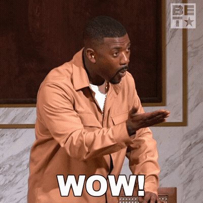 Man In Brown Shirt Saying Wow With Hands Outstretched GIF