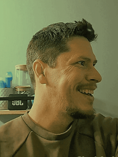 Man In Brown Shirt Smiling In Front Of JBL Speaker GIF
