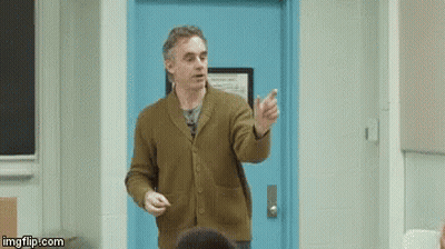 Man In Brown Sweater Lecturing Students By Blue Door GIF