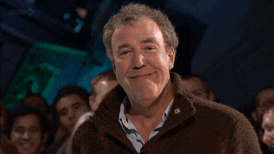 Man In Brown Sweater Smiling At Crowd GIF