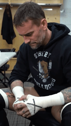 Man In Bulldog Shirt Wrapping Another Man's Hand GIF