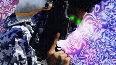 Man In Camo Jacket Holding Gun With Green Light On Face GIF