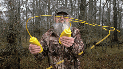 Man In Camo Jacket Holding Two Yellow Bottles GIF