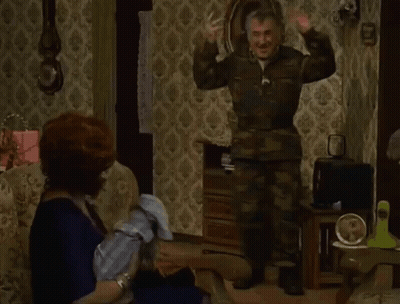 Man In Camouflage Standing In Front Of Seated Woman GIF