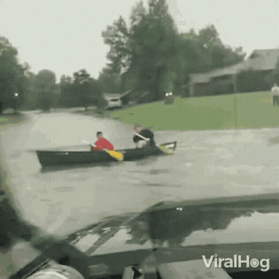 Man In Canoe Pulled By Car In Flooded Street GIF