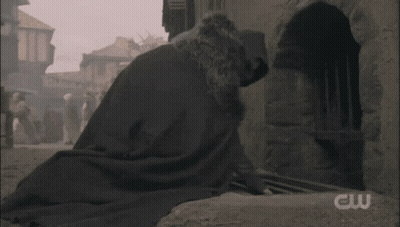 Man In Cape Walking Down Narrow Street With CW Logo GIF
