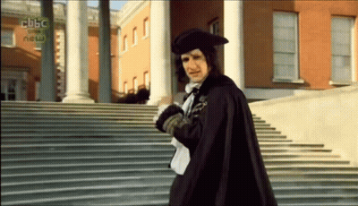Man In Cape Walking Down Stairs In Front Of BBC News Building GIF