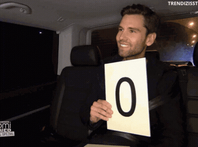 Man In Car Holding Sign Saying 0 GIF