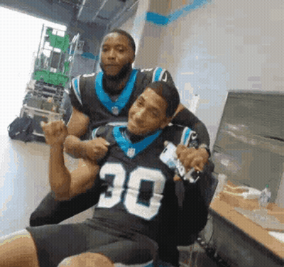 Man in Carolina Panthers Jersey Sitting With Another Man