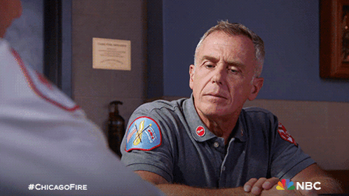 Man In Chicago Fire Uniform Sitting At Table GIF