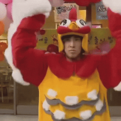 Man In Chicken Costume Holding Balloons In Front Of Store GIF