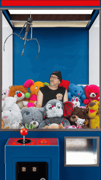 Man In Claw Machine With Stuffed Animals GIF