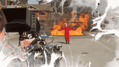 Man In Clown Costume Standing In Front Of Fire GIF