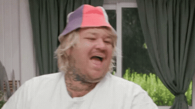 Man In Colorful Hat Making Funny Face In Living Room GIF