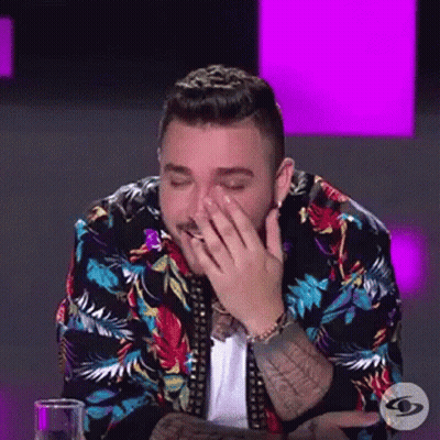 Man In Colorful Jacket Covering Face At Table GIF