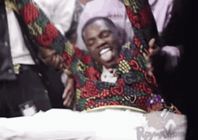 Man In Colorful Jacket Lying On Bed With Arms Outstretched GIF