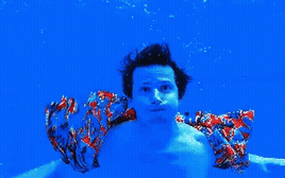 Man In Colorful Shirt Swimming Underwater In Blue Pool GIF