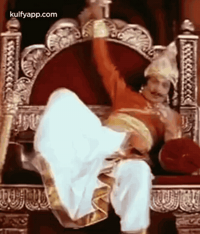 Man In Costume Sitting On Throne With Legs In Air GIF