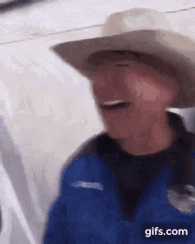 Man in Cowboy Hat and Blue Jacket Laughing on Plane