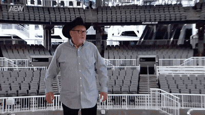 Man In Cowboy Hat And Glasses In Empty Stadium With AEW Logo GIF
