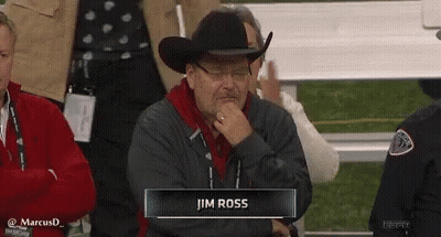 Man In Cowboy Hat And Glasses Sitting In Stadium With Jim Ross Nametag GIF