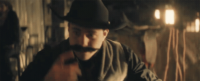 Man In Cowboy Hat And Mustache Sitting At Table GIF