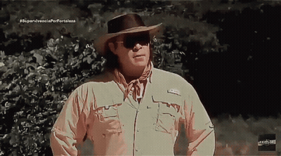 Man In Cowboy Hat And Sunglasses In Front Of Supervivencia Porfortaleza Sign GIF