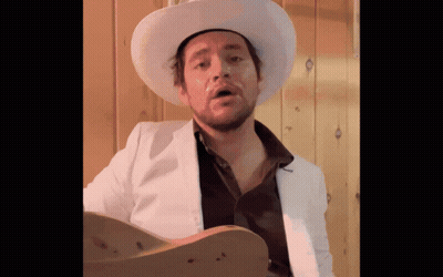 Man In Cowboy Hat And White Jacket Holding Guitar GIF