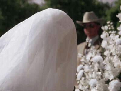 Man In Cowboy Hat Behind Bride In White Dress GIF