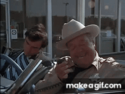 Man In Cowboy Hat Holding Gun In Front Of Make A Gitcom Sign GIF