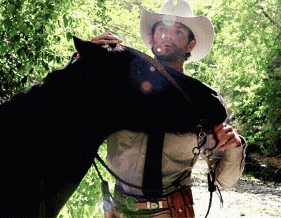 Man In Cowboy Hat Holding Horse GIF