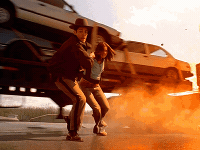 Man In Cowboy Hat Holding Woman In Front Of Stacked Cars GIF