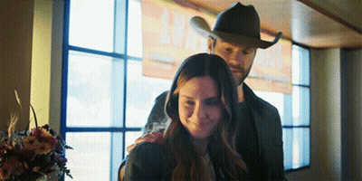 Man In Cowboy Hat Hugs Woman By Window GIF