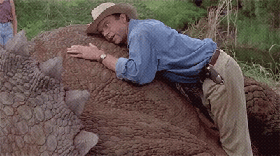 Man In Cowboy Hat Laying On Large Dinosaur Back GIF