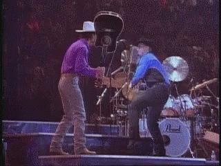 Man In Cowboy Hat Next To Woman In Blue Shirt GIF
