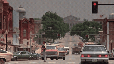 Man In Cowboy Hat On Busy Street With Red Light GIF