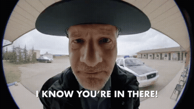Man In Cowboy Hat Says I Know You're In There In Front Of Police Car GIF