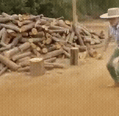 Man In Cowboy Hat Walking Near Log Pile GIF
