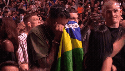 Man In Crowd Covering Face With Brazilian Flag GIF