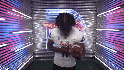 Man In Dallas Jersey Holding Football By Neon Sign GIF