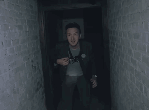 Man In Dark Hallway Holding Camera GIF