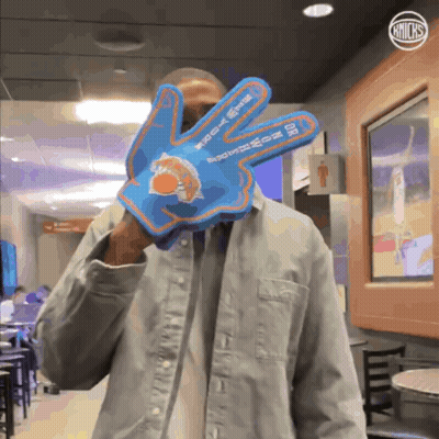 Man In Denim Jacket Holding Blue New York Knicks Glove GIF