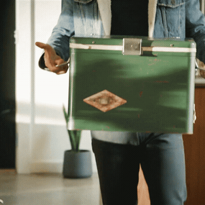 Man In Denim Jacket Holding Green Cooler With Diamond GIF