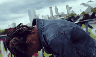 Man In Denim Jacket Kneeling In Front Of Mercedes Sign GIF