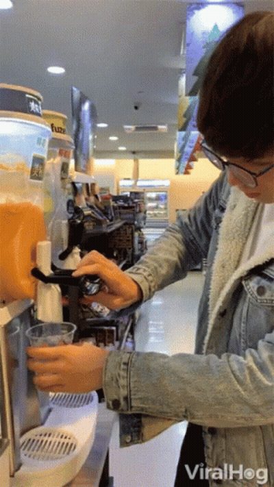 Man In Denim Jacket Pouring Orange Juice At Vending Machine GIF
