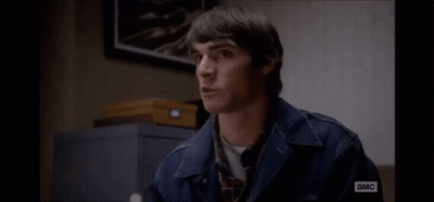 Man In Denim Jacket Sitting By Sign Saying I Am A MC GIF