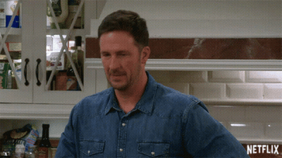 Man In Denim Shirt Next To Netflix Sign GIF
